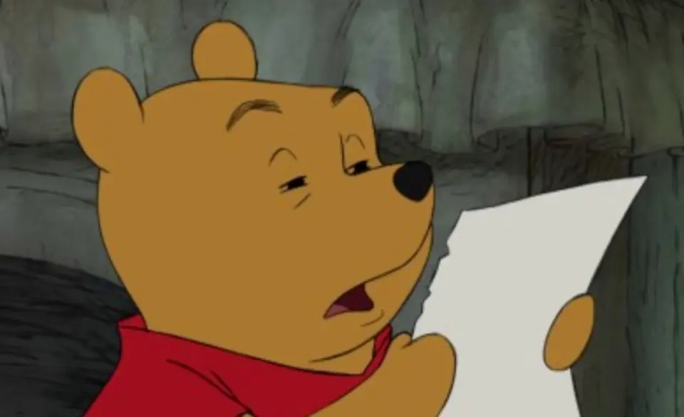 Cartoon yellow bear in a red shirt squinting at a sheet of paper, mouth slightly open in puzzlement