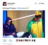 Tweet screenshot captioned "Michael Phelps. #Olympics" showing a hooded athlete firing a laser beam at a rival's flaming hair