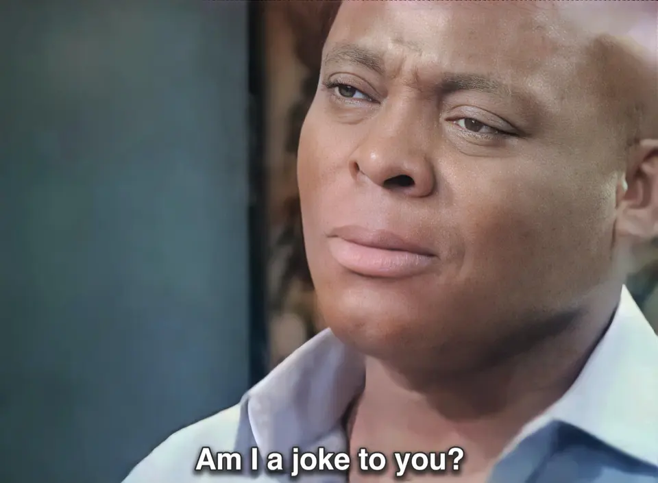 Close-up of a person in a blue collared shirt glancing sideways with a hurt look, subtitled "Am I a joke to you?"