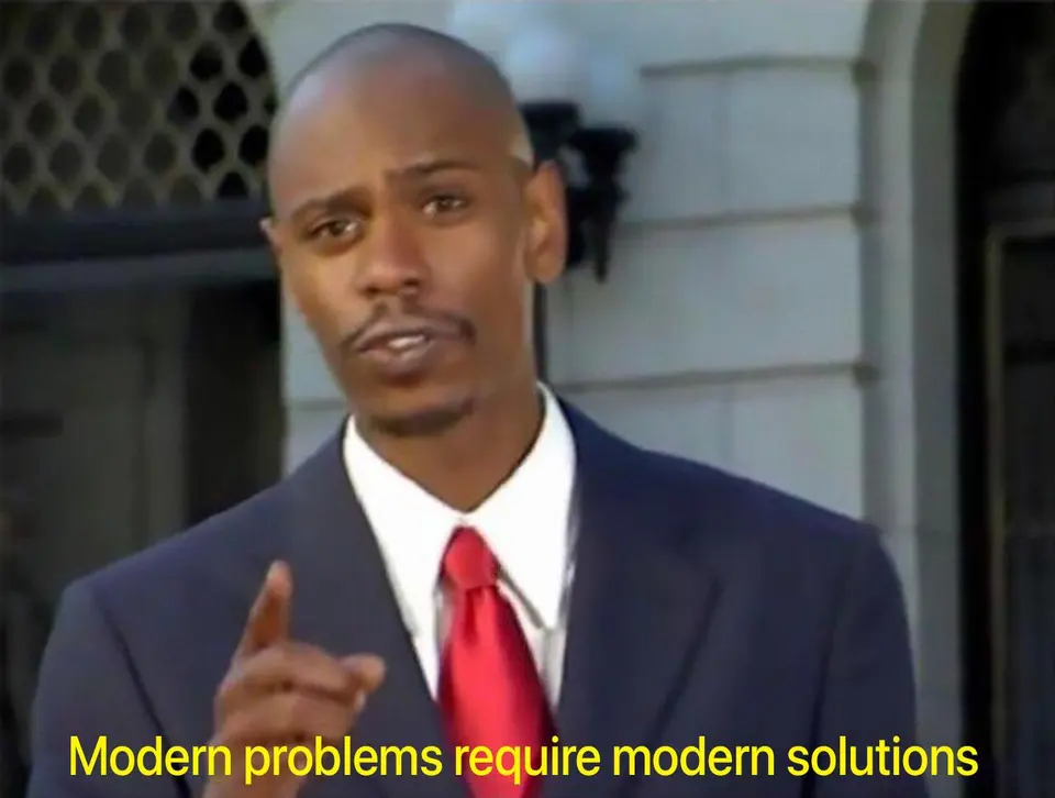 Man in a navy suit and red tie pointing while speaking outdoors, yellow caption "Modern problems require modern solutions"