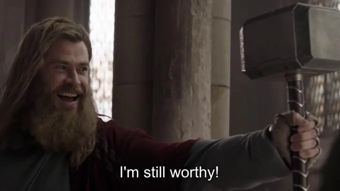 Long-haired bearded man in a red cape grinning as he holds a war hammer aloft, subtitled "I'm still worthy!"