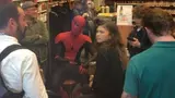 Candid on-set photo: a seated Spider-Man in costume gestures while a young woman with curly hair looks unimpressed