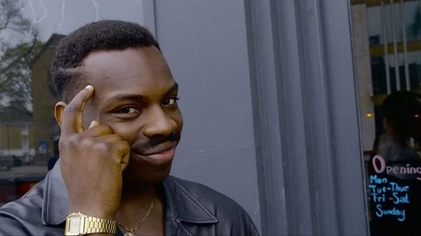 A man tapping his temple with a knowing smirk